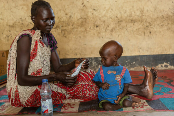 Mother is Feeding her child with plumbee nuts at a health facility in Bentiu.